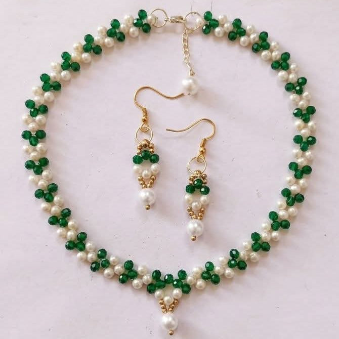 Green and white beaded necklace with matching earrings on a light gray background