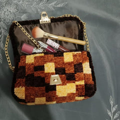 Checkered patterned handbag with makeup items on a textured gray background