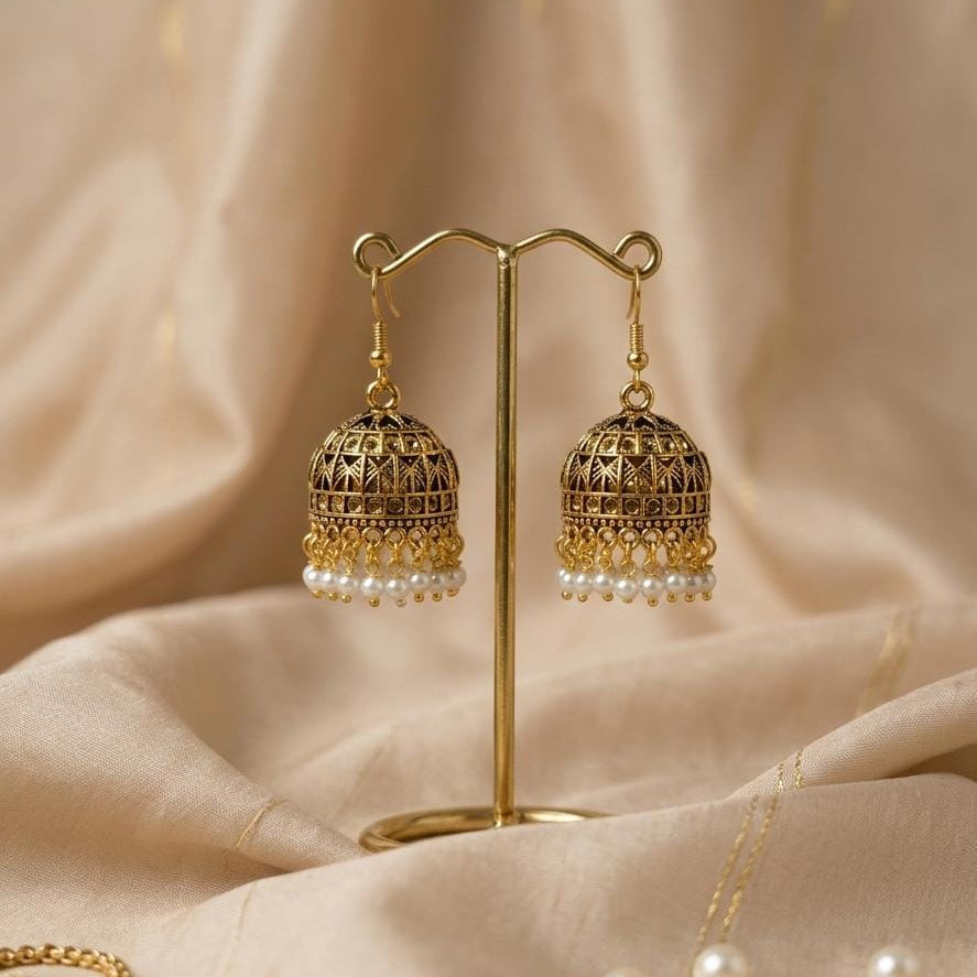 Gold earrings with pearl drops on a beige fabric background