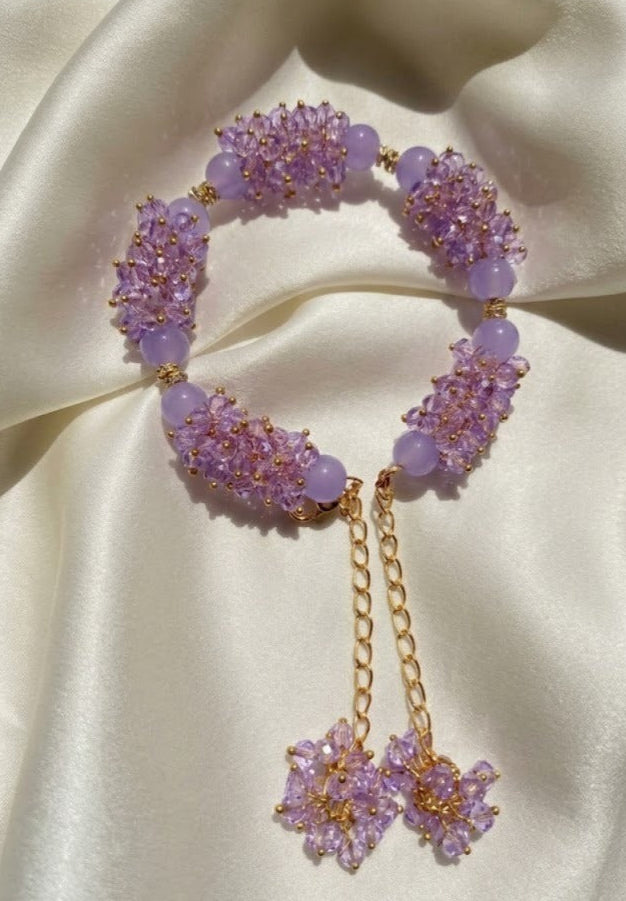 Purple beaded bracelet with gold chain on a satin surface