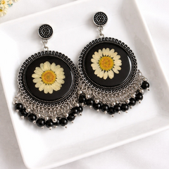 Black earrings with floral designs on a white plate