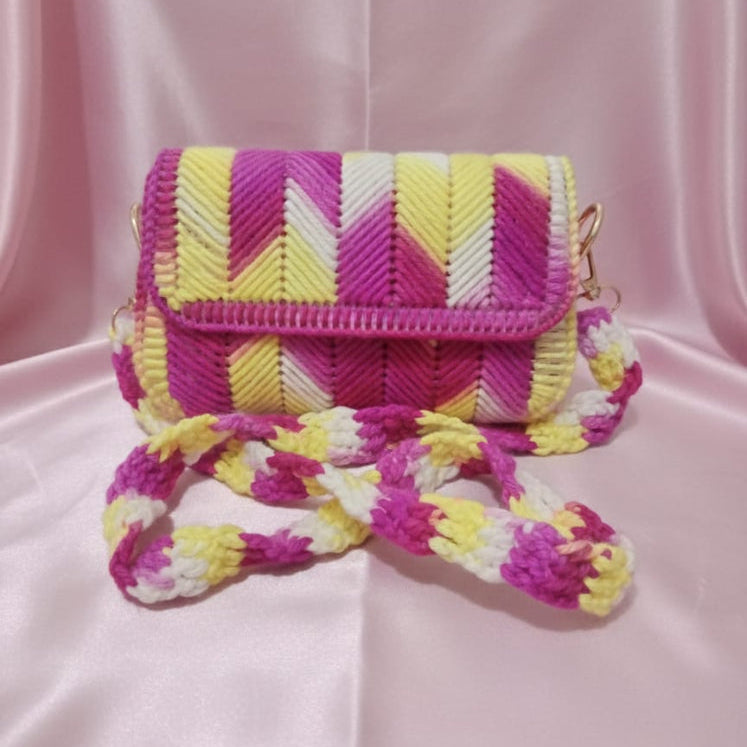 Colorful woven handbag with a strap on a pink background